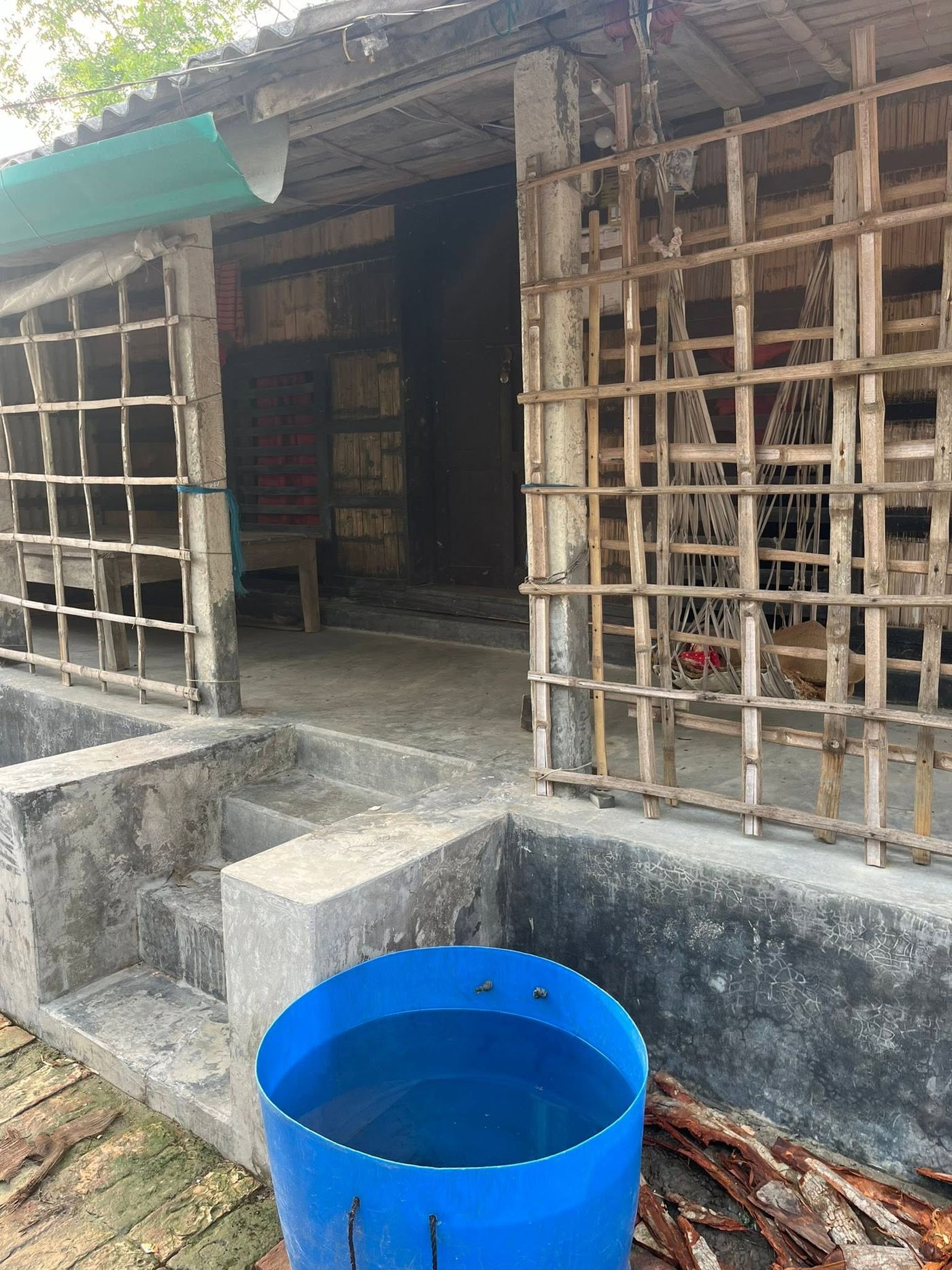 Household rainwater tank beside a bamboo structure