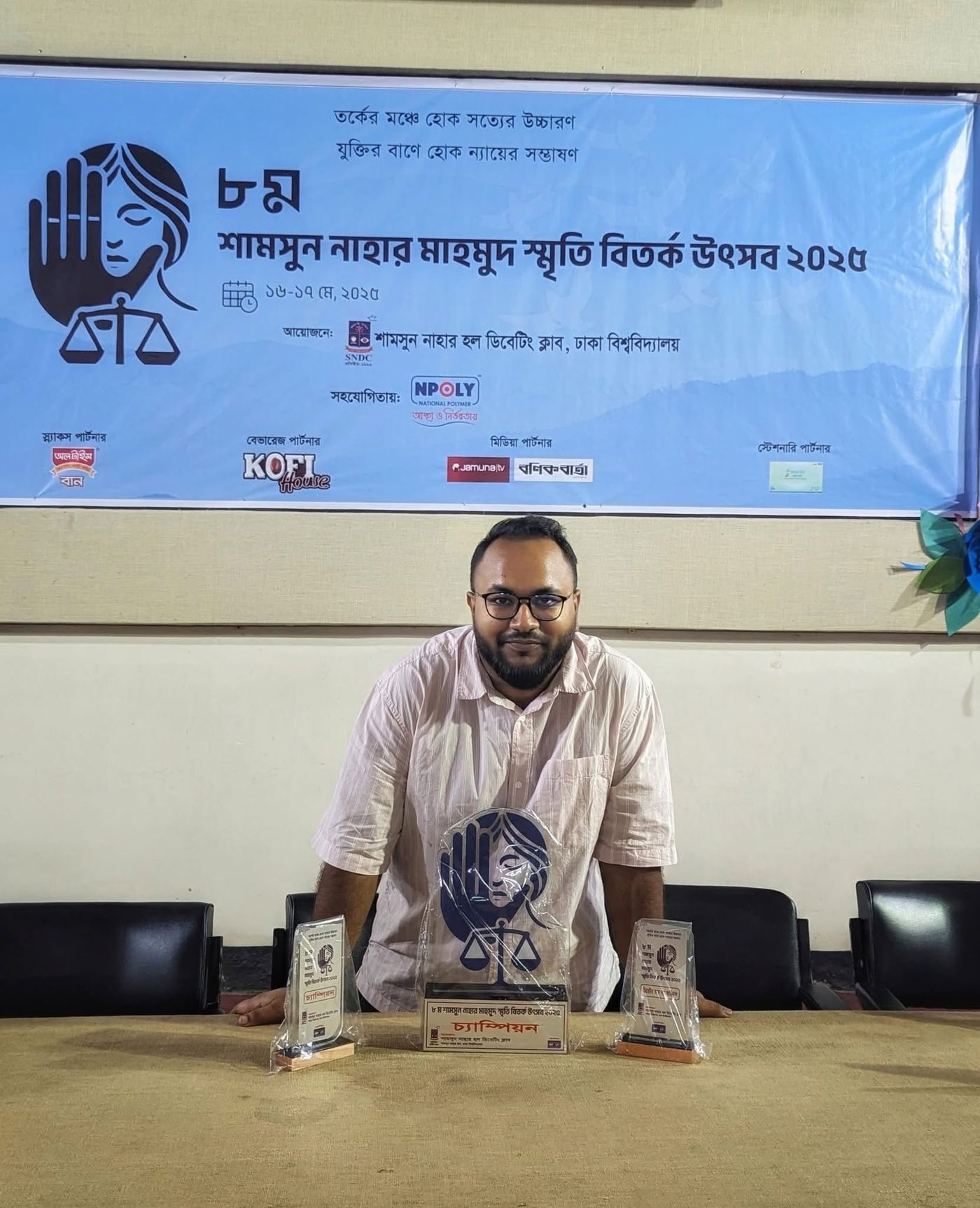 Hasib seated behind his trophies at the debate festival