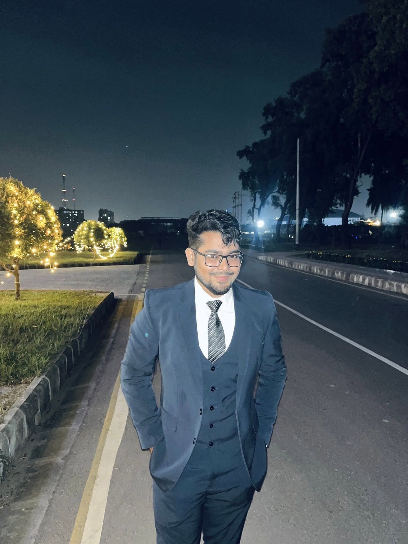 Fahim in a suit standing by a road at night