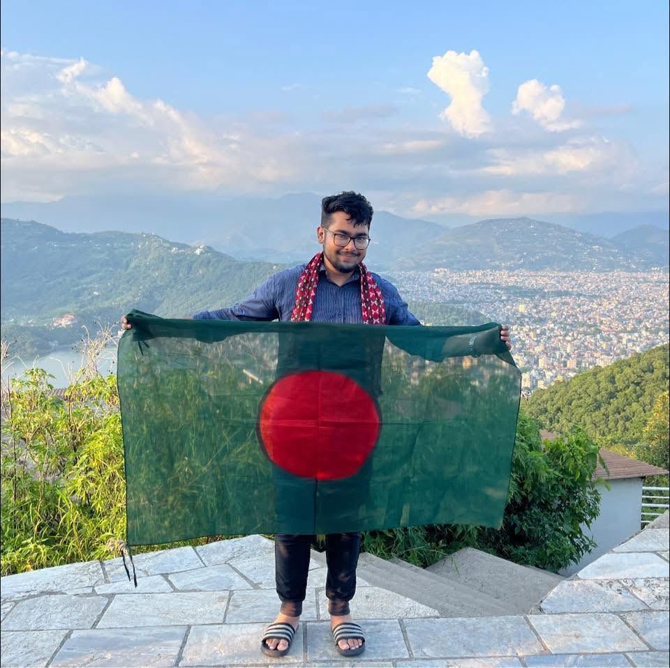 Fahim holding the Bangladesh flag above a valley