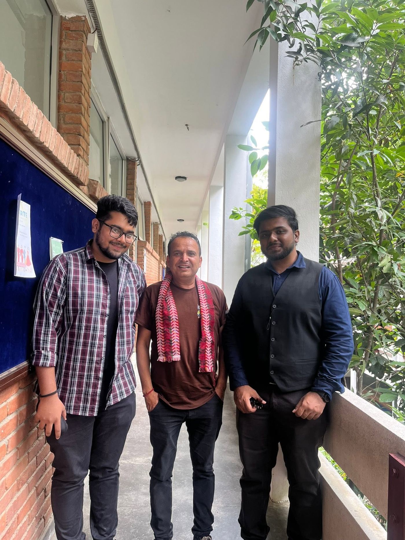 Three people standing in a corridor at Kathmandu University
